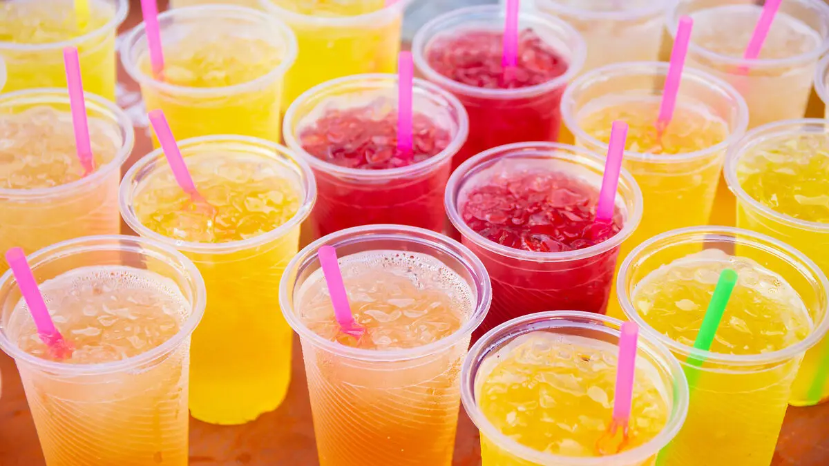 Mehrere Becher mit gelbem, orangefarbenem und rotem Slush Ice stehen nebeneinander.