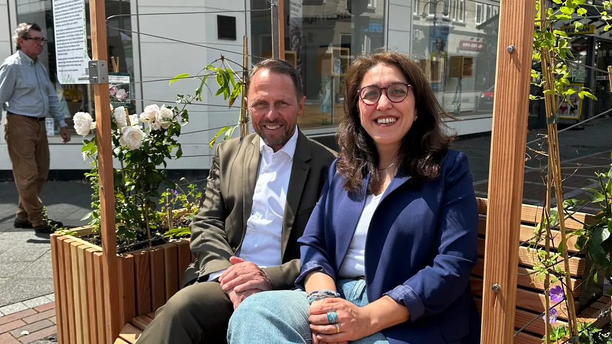 Fatma Özkan (Leiterung Gruppe Klimaanpassung VZ NRW) und Uwe Richrath (Oberbürgermeister Leverkusen) sitzen auf den Ausstellungsmöbeln