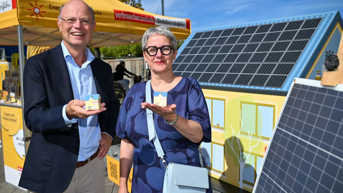 Silke Krebs, Staatssekretärin im Ministerium für Wirtschaft, Industrie, Klimaschutz und Energie des Landes Nordrhein-Westfalen und Wolfgang Schuldzinski, Vorstand der Verbraucherzentrale NRW zeigen kleine Modelle eines Hauses mit einem Stand der Verbraucherzentrale im Hintergrund
