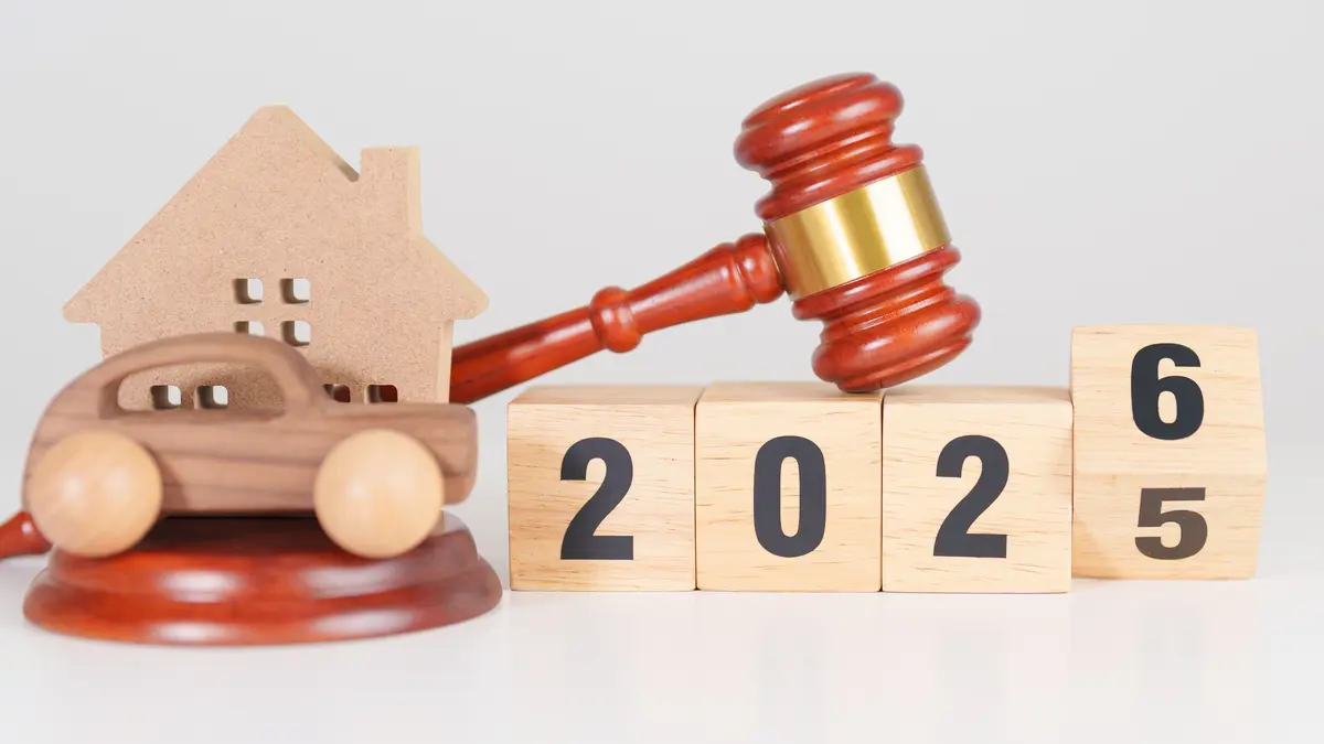 Holzspielzeug mit Aufschrift "2026" sowie ein Holzhaus, ein Holzauto und ein Gerichtshammer