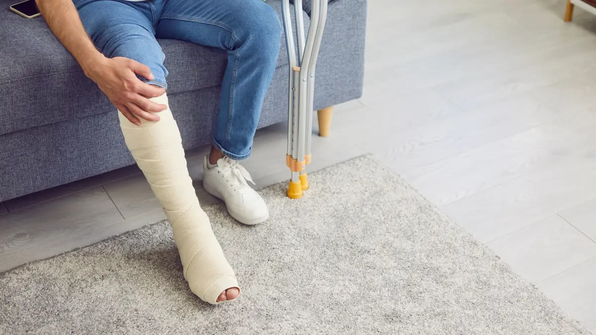 Mann sitzt auf Sofa mit verletztem Bein