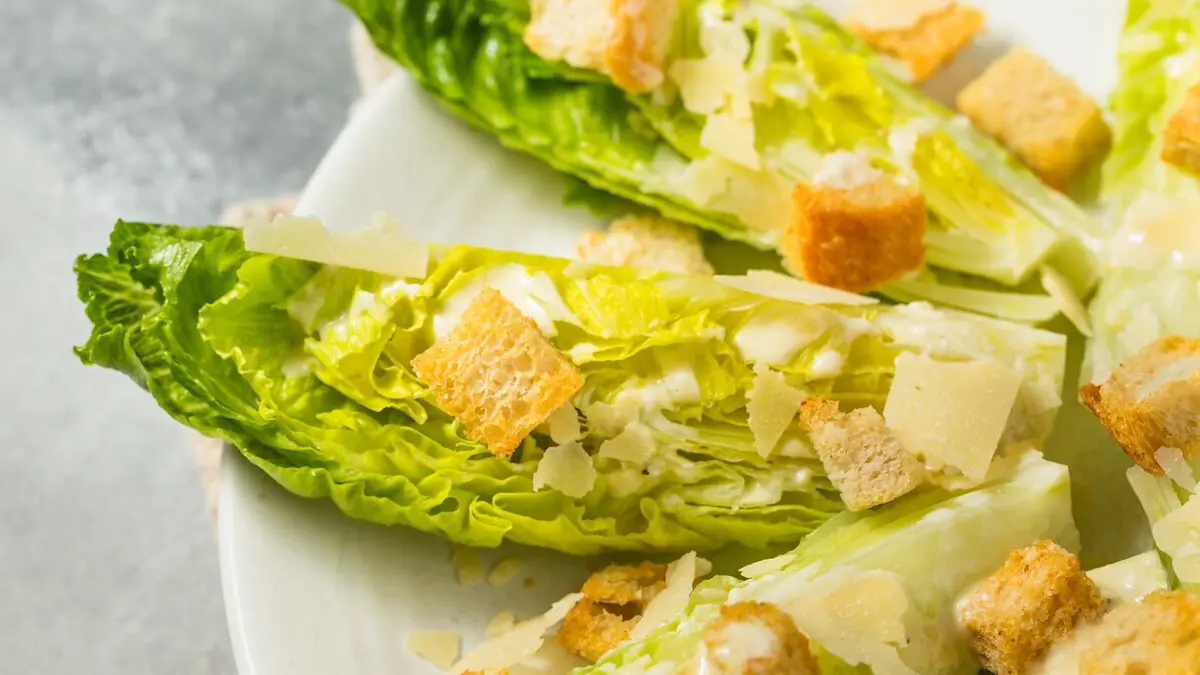 Romana-Salatblätter mit Croûtons auf einem weißen Teller.