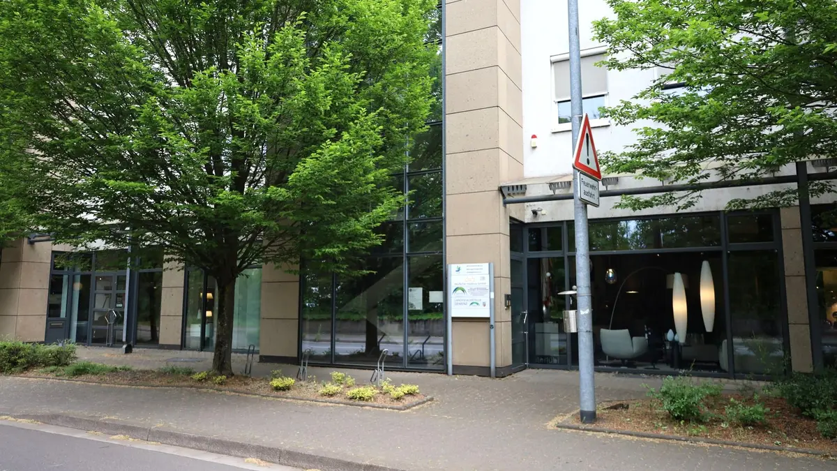 Gebäue an Straße mit Bäumen davor und Schaufenster eines Lampengeschäfts