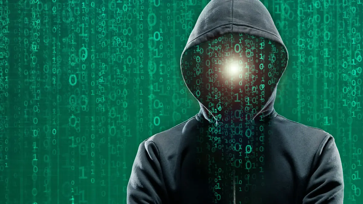 Hacker in Hoodie vor einem Bildschirm