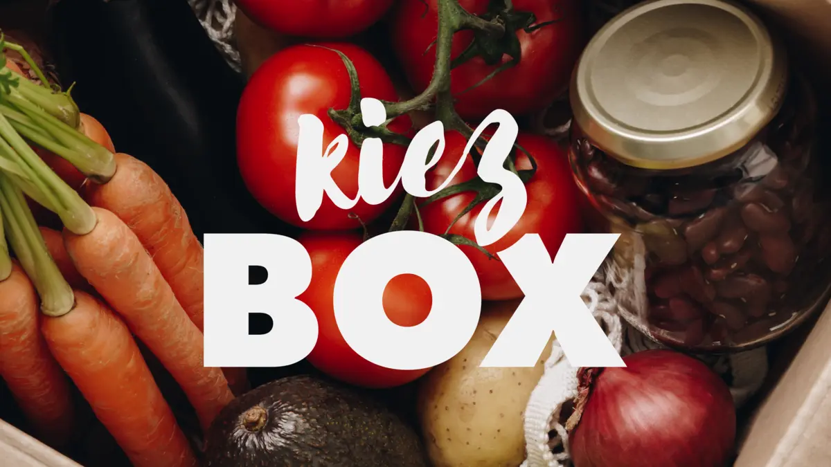 Eine Kiste mit Lebensmitteln, darüber der Schriftzug "Kiez-Box"