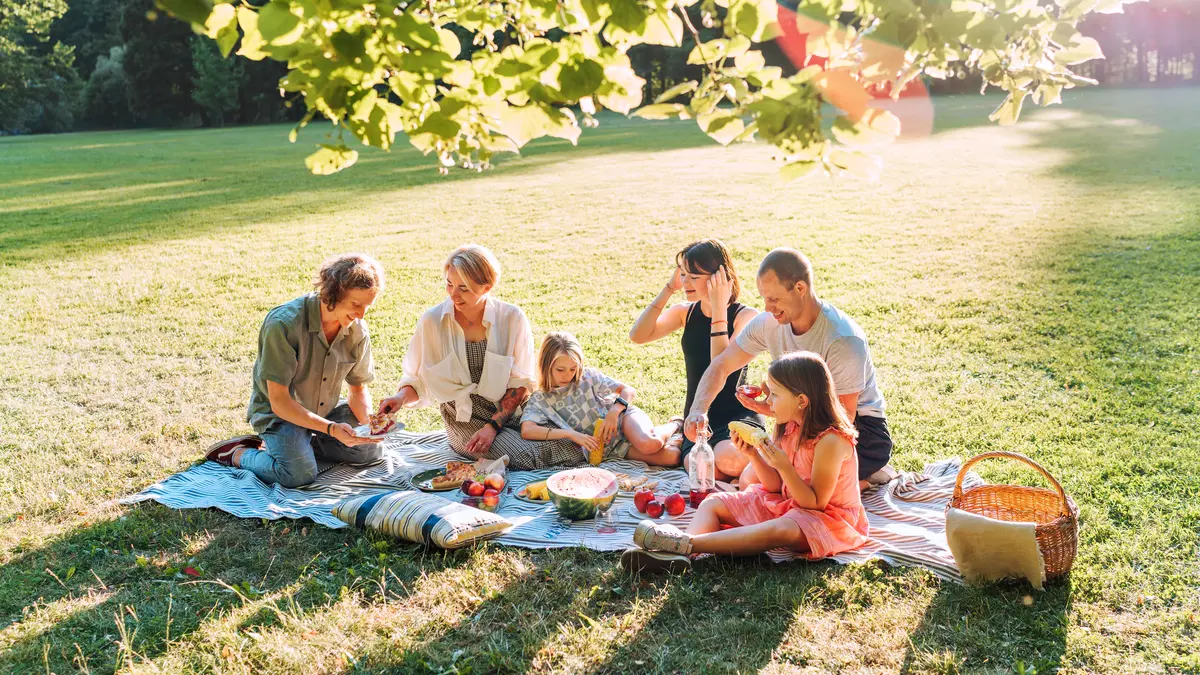 Eine Gruppe von Menschen macht ein Picknick im Park bei sommerlichen Temperaturen