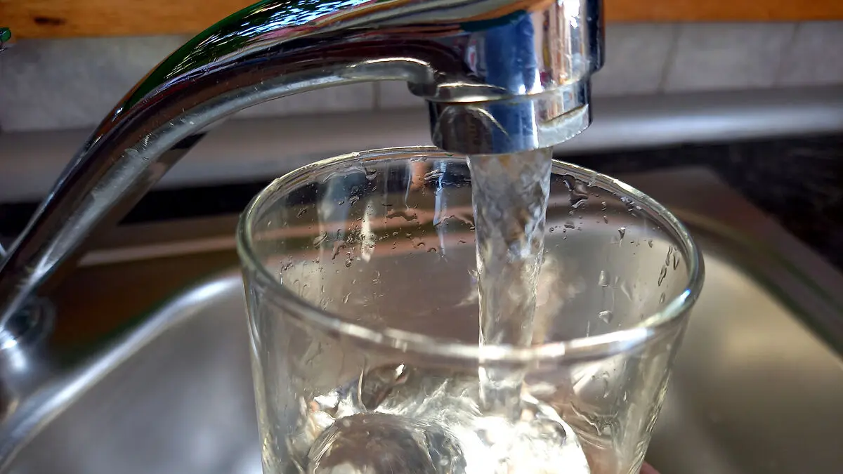Aus einem Wasserhahn läuft Leitungswasser in ein Glas.
