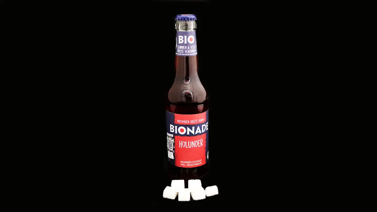 Flasche Bionade Holunder auf schwarzem Grund mit 5,5 Zuckerwürfeln davor