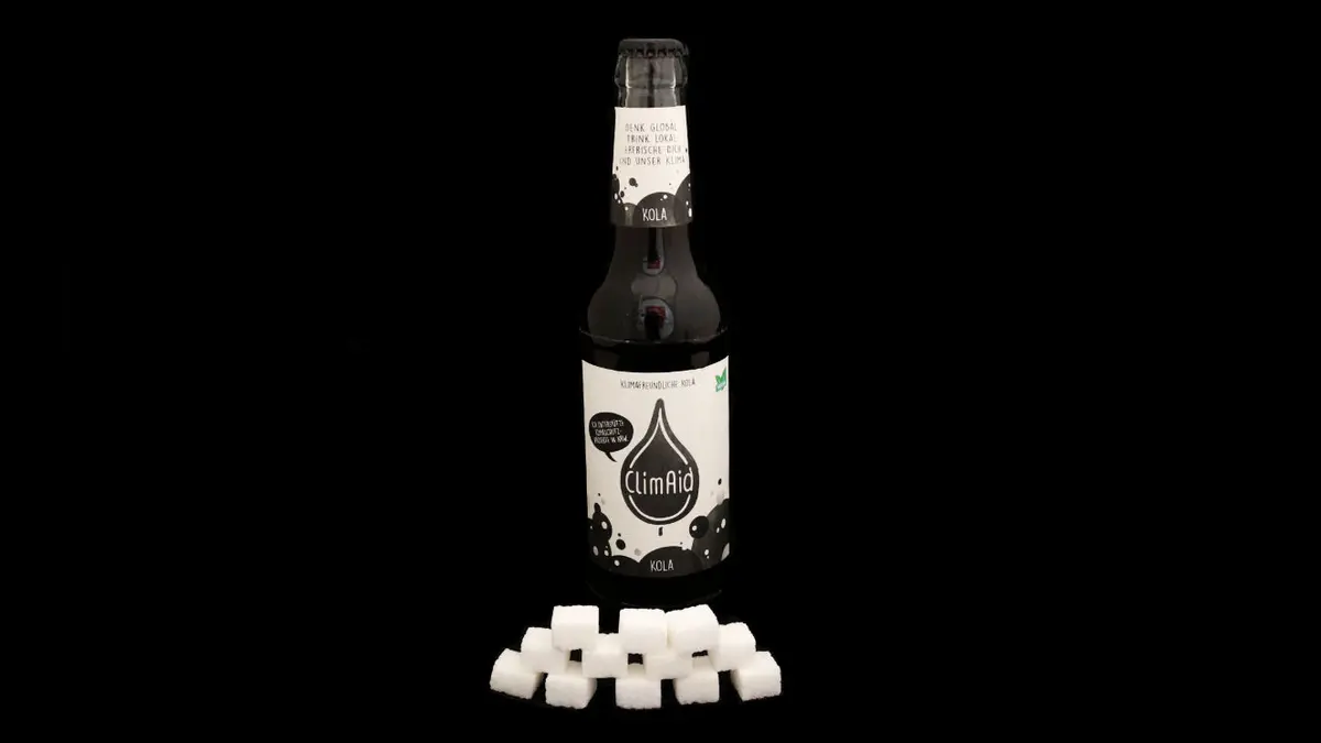 Flasche ClimAid auf schwarzem Grund mit 12 Zuckerwürfeln davor