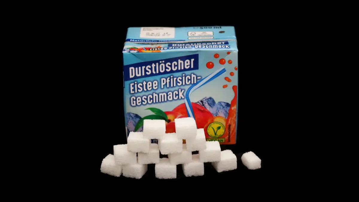 Packung durstlöscher eistee pfirsich auf schwarzem Grund mit 14,5 Zuckerwürfeln davor