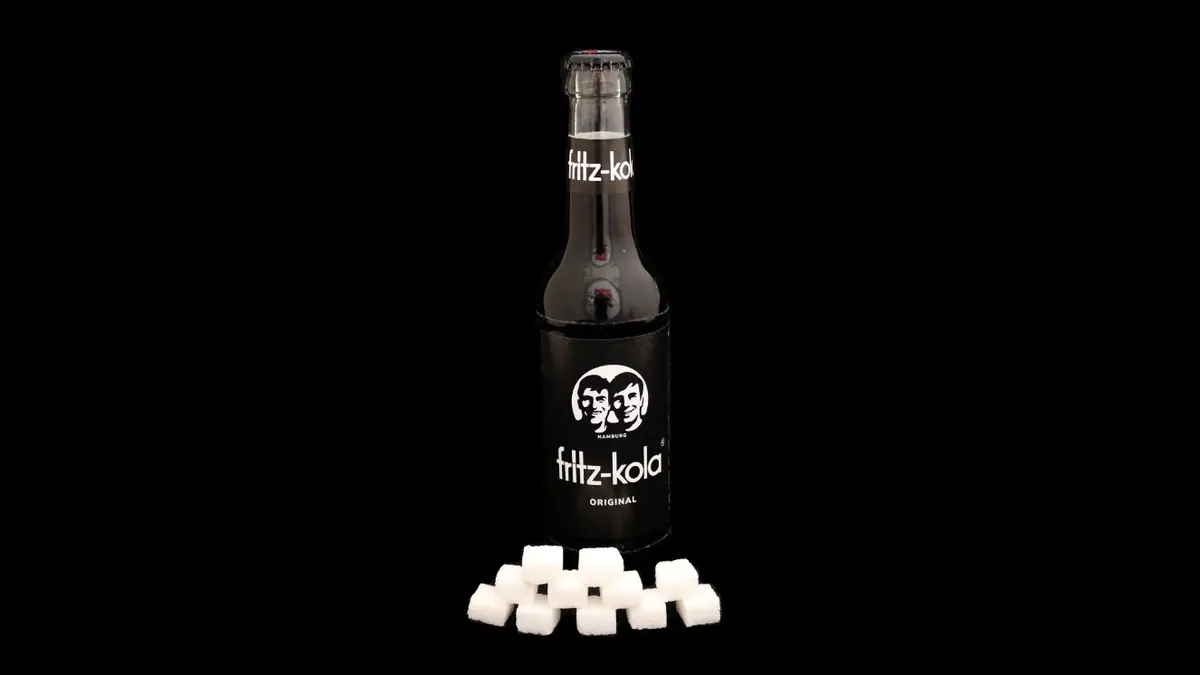 Flasche Fitz Cola auf schwarzem Grund mit 11 Zuckerwürfeln davor