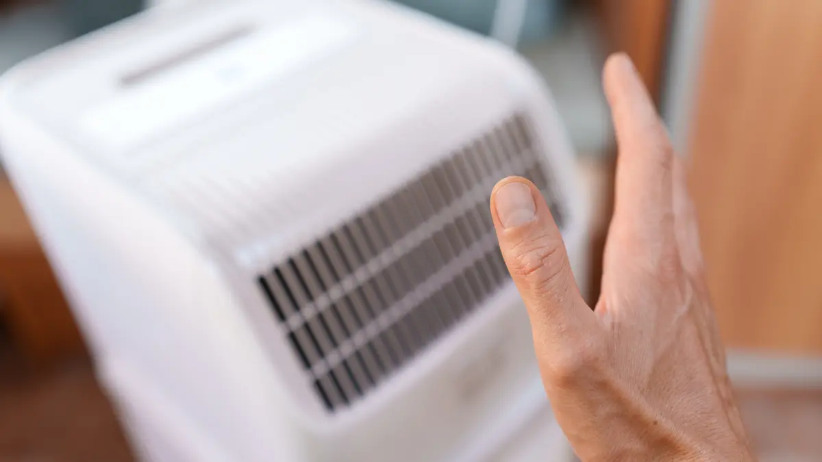 Ein Mann hält seine Hand zum Kühlen an eine mobile Klimaanlage