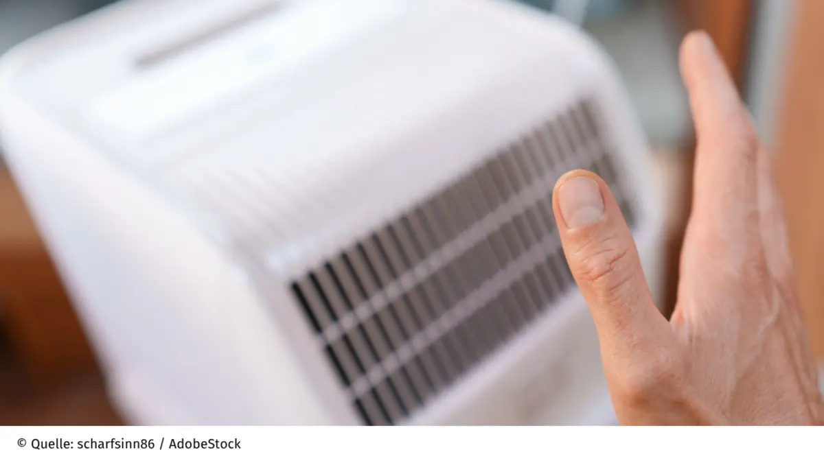 Ein Mann hält seine Hand zum Abkühlen an eine mobile Klimaanlage