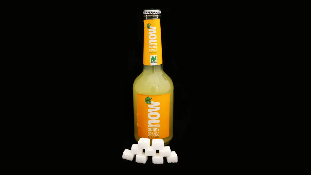 Flasche Lammsbräu auf schwarzem Grund mit 9 Zuckerwürfeln davor