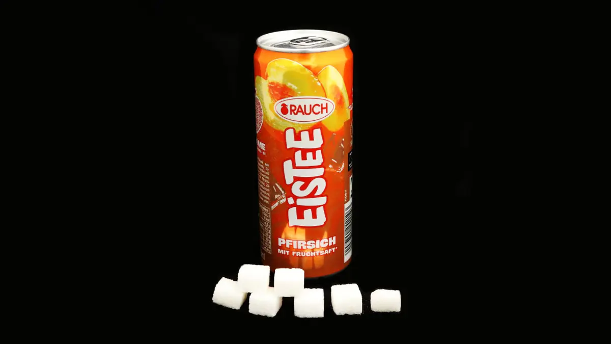 Dose Rauch Eistee auf schwarzem Grund mit 10 Zuckerwürfeln davor