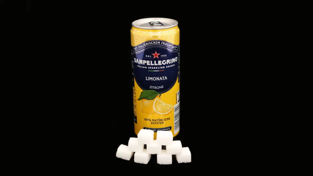 Dose San Pellegrino Zitrone auf schwarzem Grund mit 9 Zuckerwürfeln davor