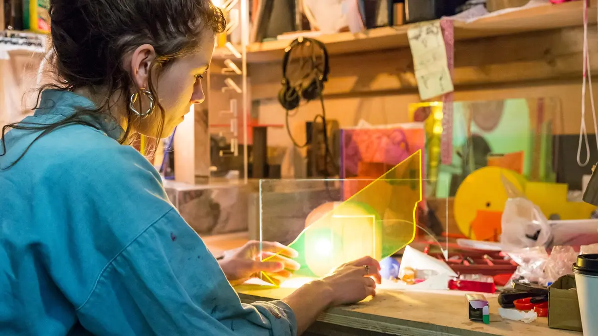 Eine junge Frau arbeitet in einer Werkstatt mit Plexiglas-Platten.