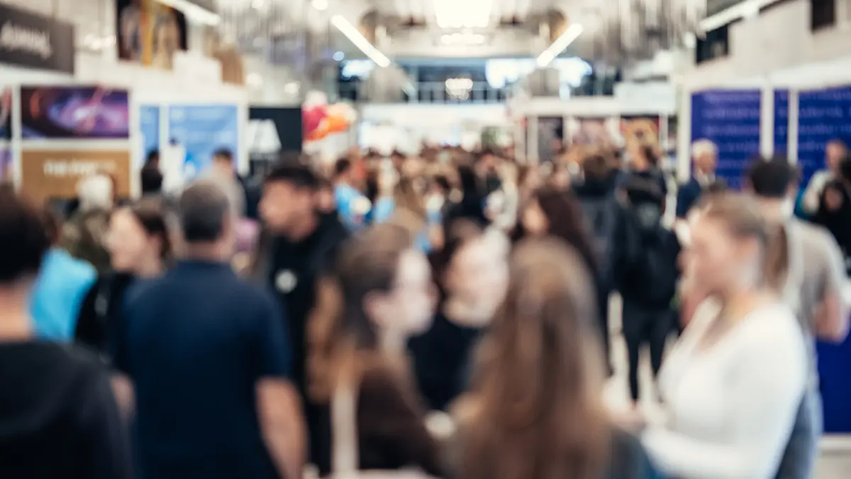 Volle Messehalle mit viele Ständen und Menschen