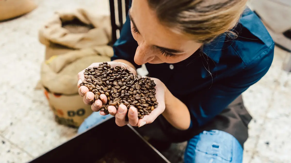 Frau riecht an Kaffeebohnen