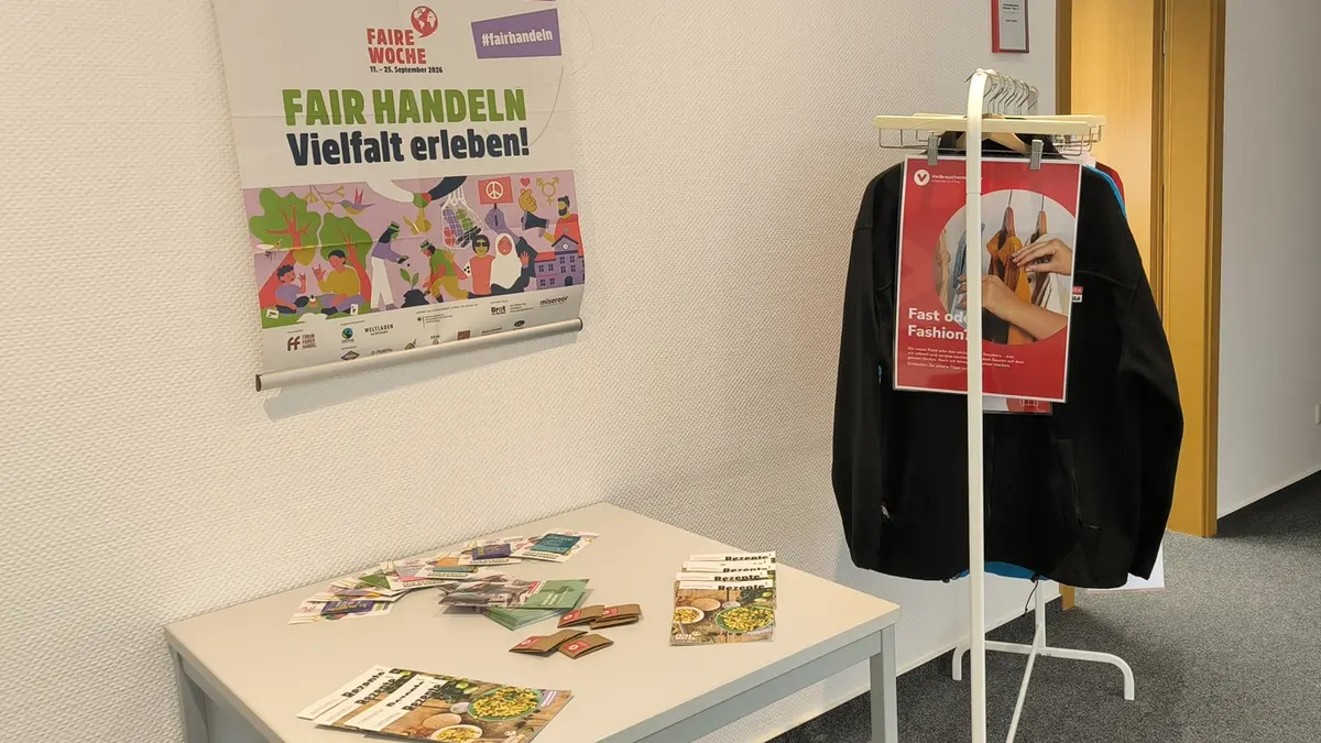 Info-Ecke zum Thema Fair Trade mit Plakaten und einer Kleiderstange