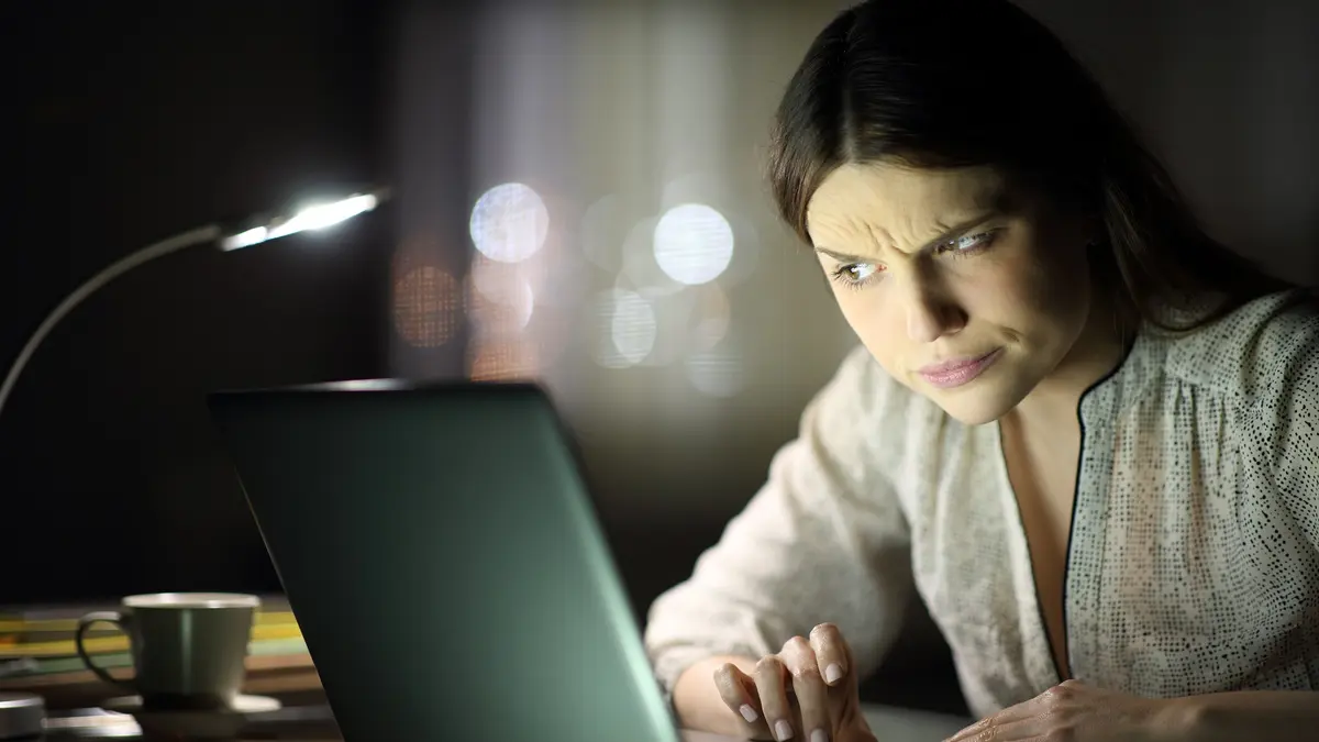 Frau blickt konzentriert und skeptisch auf einen Laptop.