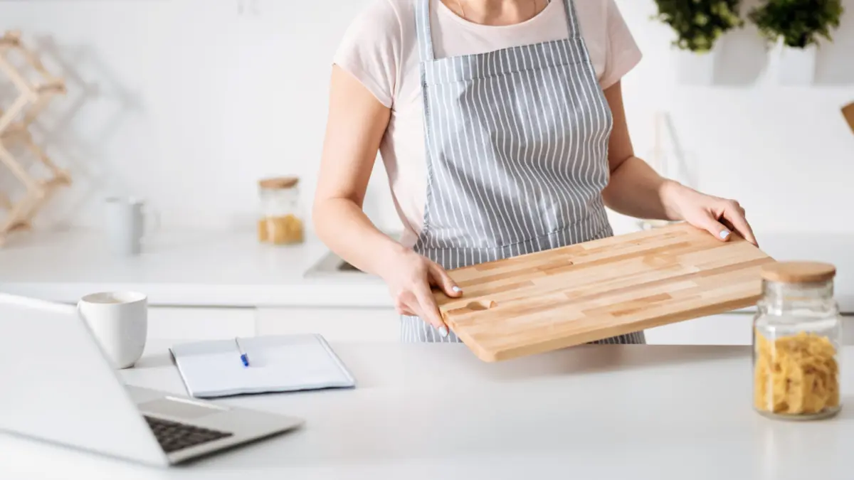 Frau bereitet sich auf Kochen vor, legt Brett auf Arbeitsplatte. 