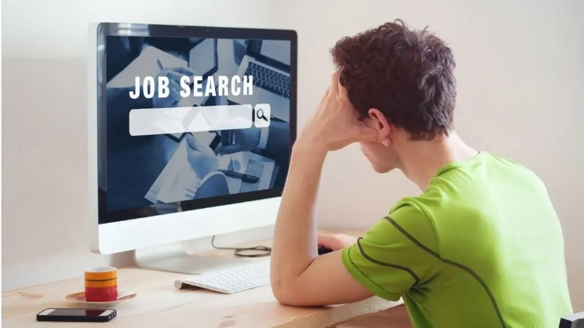 Mann sitzt am Schreibtisch, vor ihm ein großer Bildschirm mit der aufschrift Job search