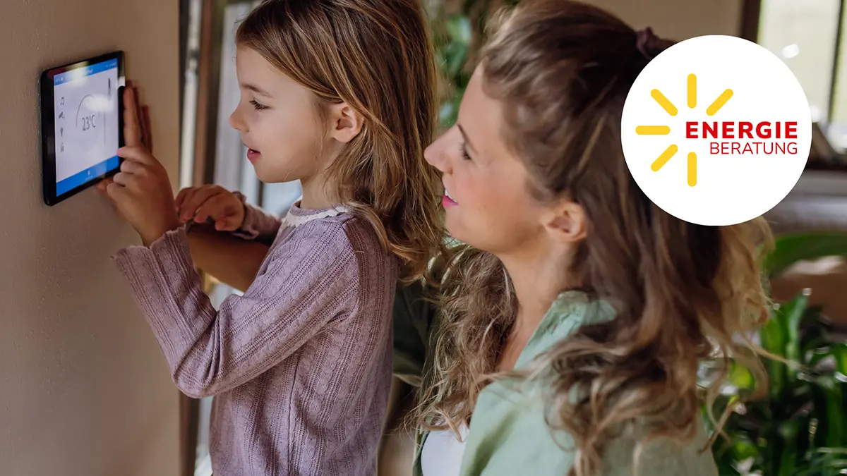 Mutter und Tochter stellen Heizung am modernen Wandthermostat ein.