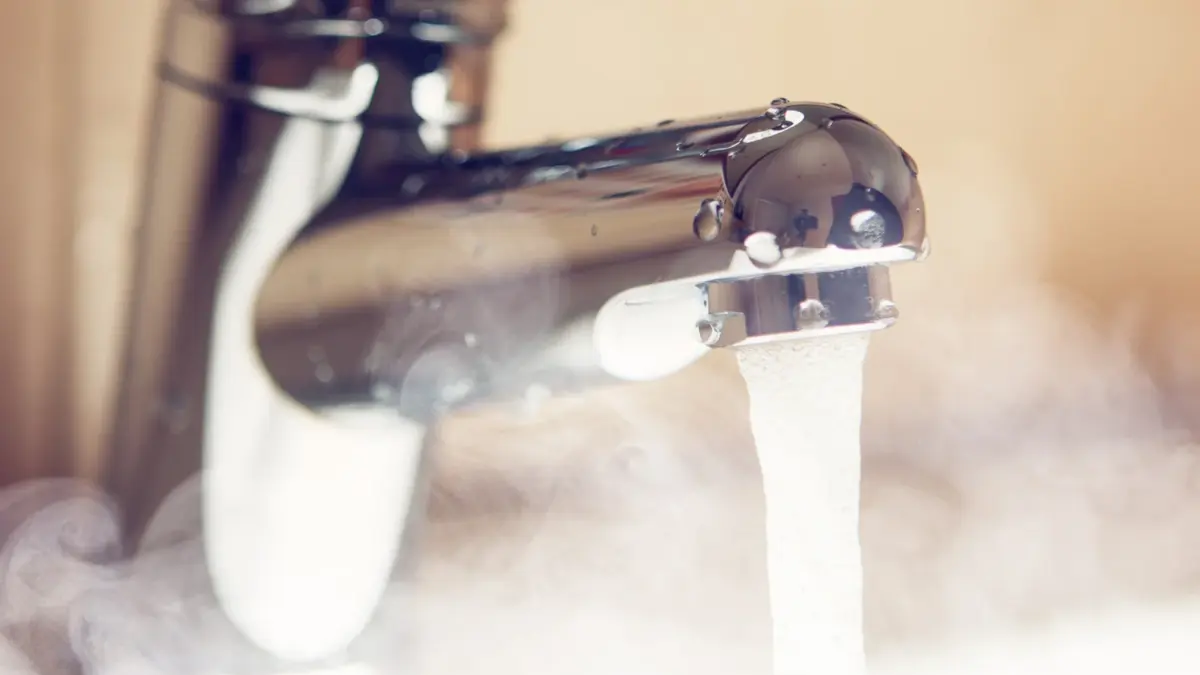 aus einem Wasserhahn fließt heißes, dampfendes Wasser