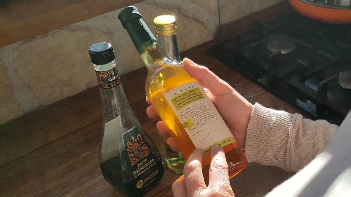 Eine Person betrachtet das Etikett auf der Rückseite einer Essigflasche.