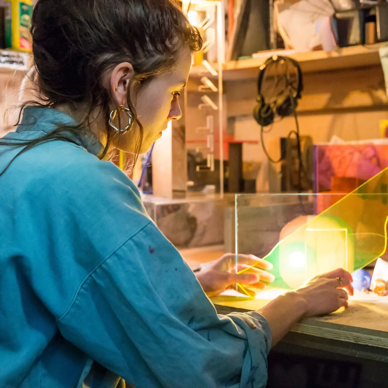 Eine junge Frau arbeitet in einer Werkstatt mit Plexiglas-Platten.
