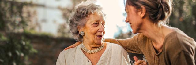 eine ältere und eine jüngere Frau sitzen im Garten und reden