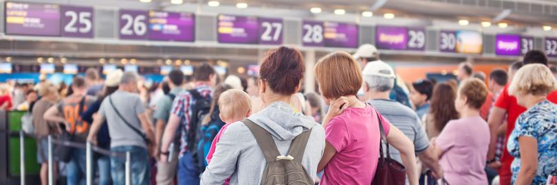 Eine Schlange von Menschen steht vor einem Schalter am Flughafen.