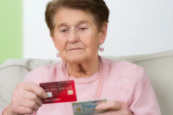 Seniorin schaut sich ihre Krankenkasse Versichertenkarte an