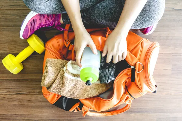 Fitnessstudio - Frau packt ihre Trinkflasche in die Tasche