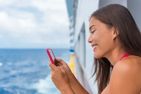 Eine Frau nutzt ihr Smartphone auf einem Kreuzfahrtschiff