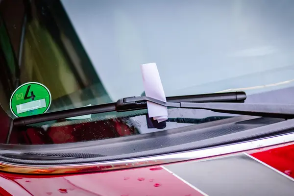 Hinter einem Scheibenwischer klemmt ein Knöllchen am Auto