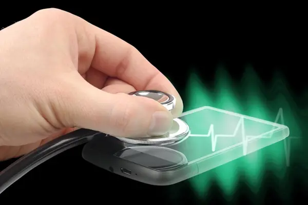 Hand hält Stethoskop auf Smartphone-Display, dazu eine Herzstromkurve