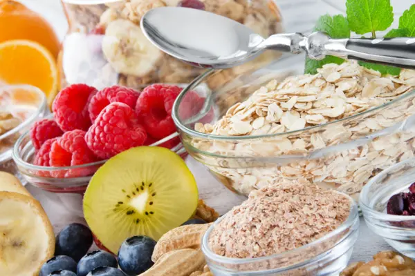 Obst, Nüsse und Müsli stehen auf einem bunt gedeckten Tisch