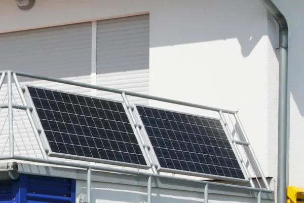 Außen an dem Geländer eines Balkons sind zwei Solarmodule montiert.