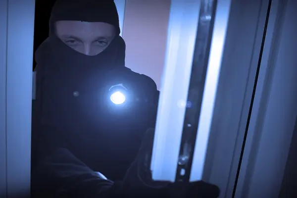 Mann bricht über ein Fenster in eine Wohnung ein.