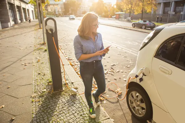 Junge Frau neben E-Auto