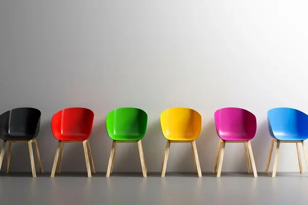 Bunte Stühle vor einer weißen Wand.