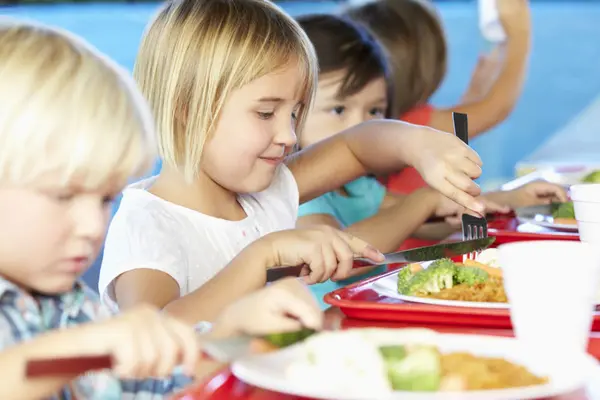 Kinder sitzen an einem Tisch und essen