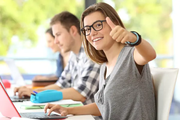 Studenten sitzen in einem Vorlesungsraum vor ihrem Laptop.