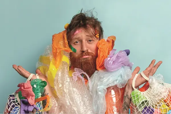 Mann mit Plastiktüten und Plastikflaschen behängt.