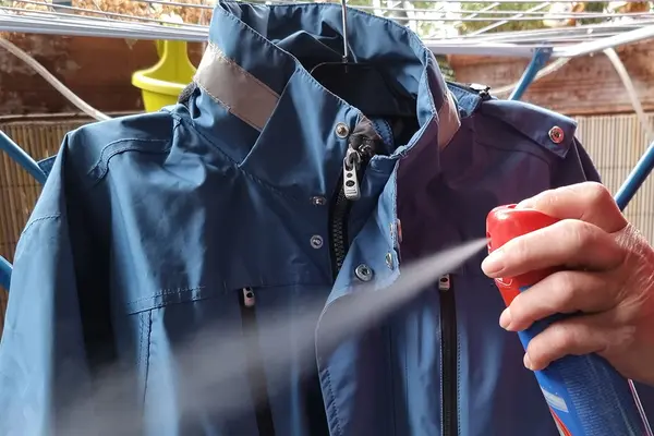 Imprägnierspray wird auf hellblaue Regenjacke gesprüht