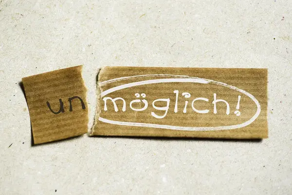 Ein Zettel, an dem links ein Stück abgerissen ist. Auf dem abgerissen Stück steht un und auf dem Rest möglich.