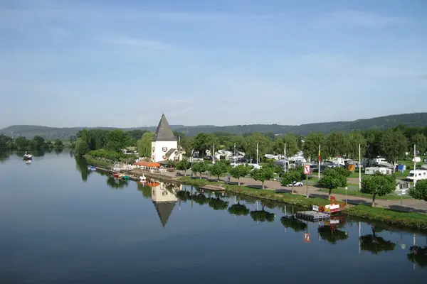 Links im Bild fließt ein Fluss; rechts im Bild ist eine Uferpromenade mit einem Turm.