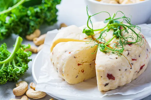 Ein veganer Käse aus Cashewkernen liegt auf einem Teller